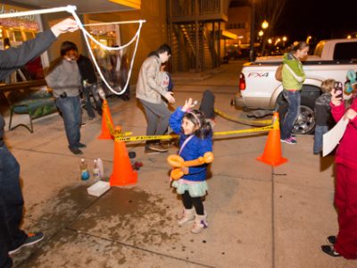 A little girl pops a giant bubble at First Friday.